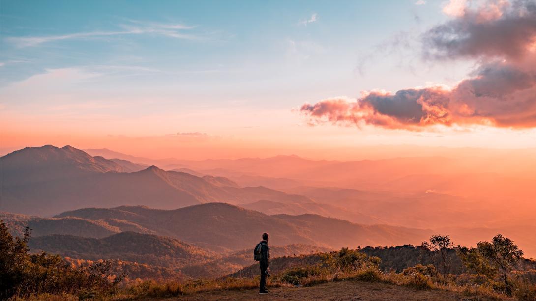 Person standing on a hill overlooking natural scene